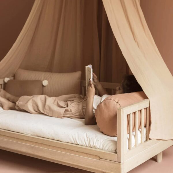 Studio lighting, perspective view of a bedroom with a kids' wooden bed frame with a fabric canopy fixed on the top.