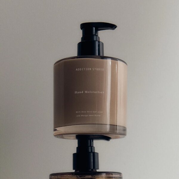 Studio lighting, perspective view of two bottles of hand moisturisers placed on top of another bottle's squeeze pump.