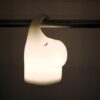 Dimly lit background, perspective view of a lit animal-shaped lamp hanging on a tube.