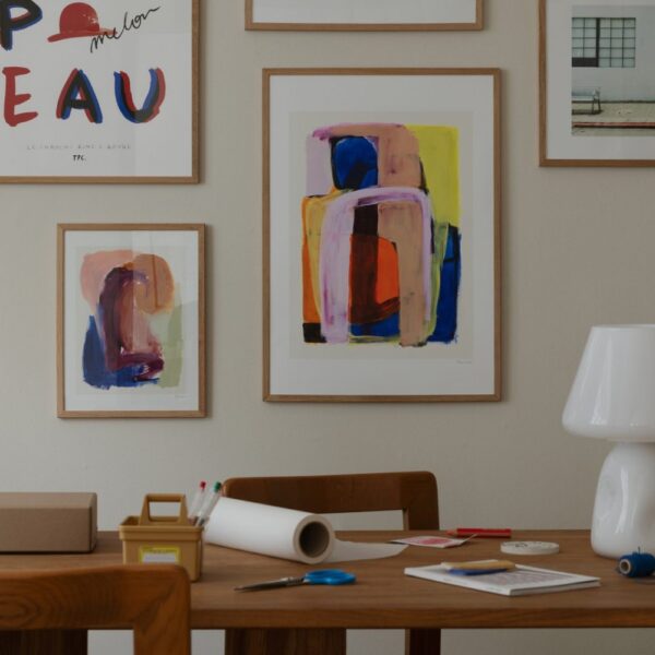Natural lighting, perspective view of a framed abstract art print hung on a wall next to other art prints.