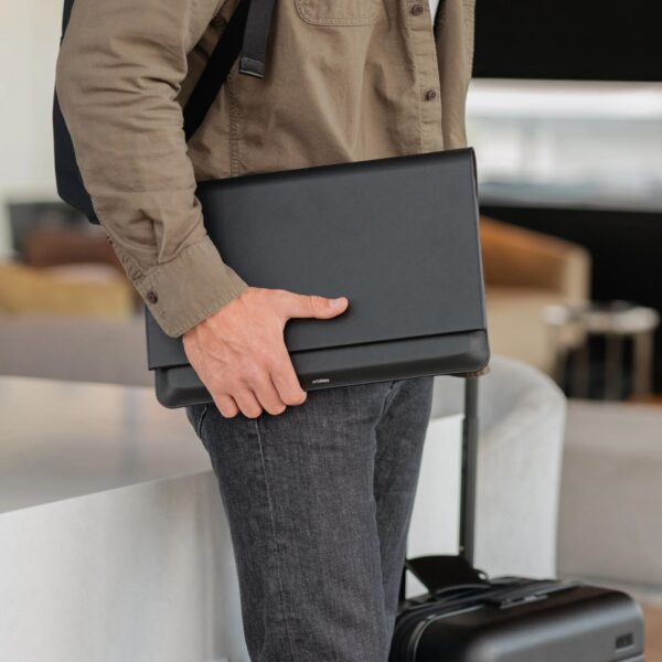 A standing person clutching a laptop sleeve on their hips,