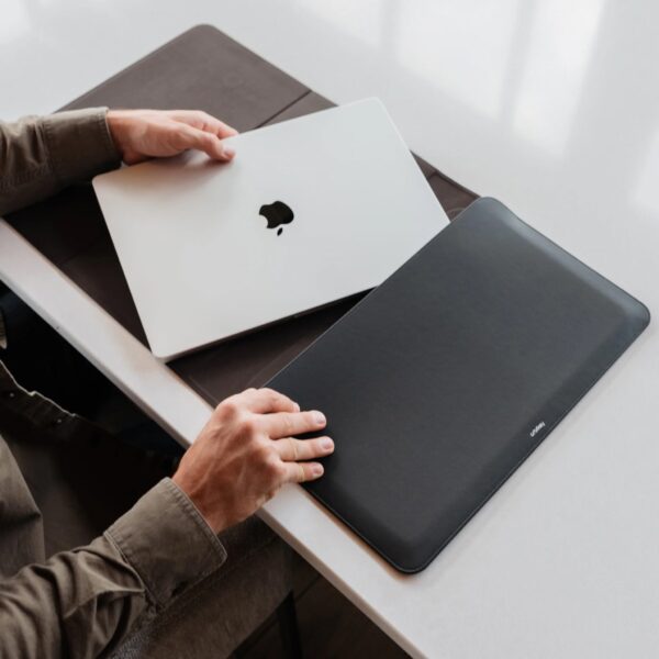 Over-the-shoulder view of a seated person getting their laptop out of the laptop sleeve,