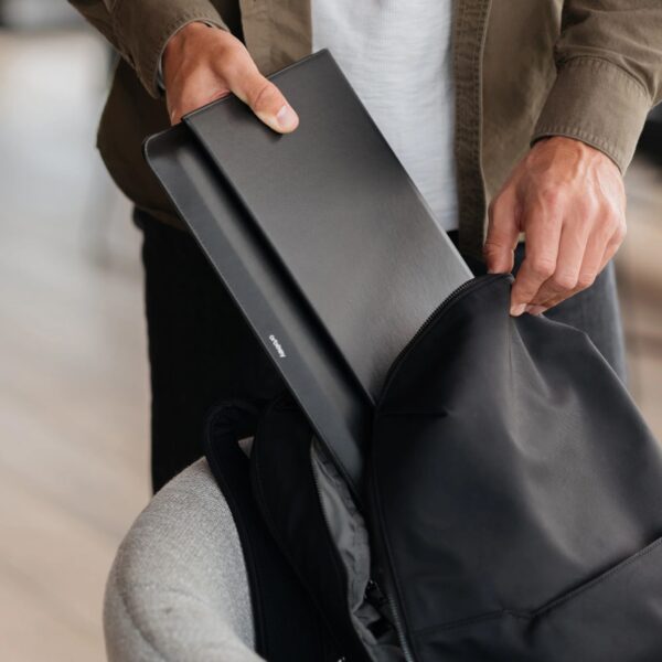 Cropped view of a person putting their laptop sleeve inside a backpack's inner compartment,